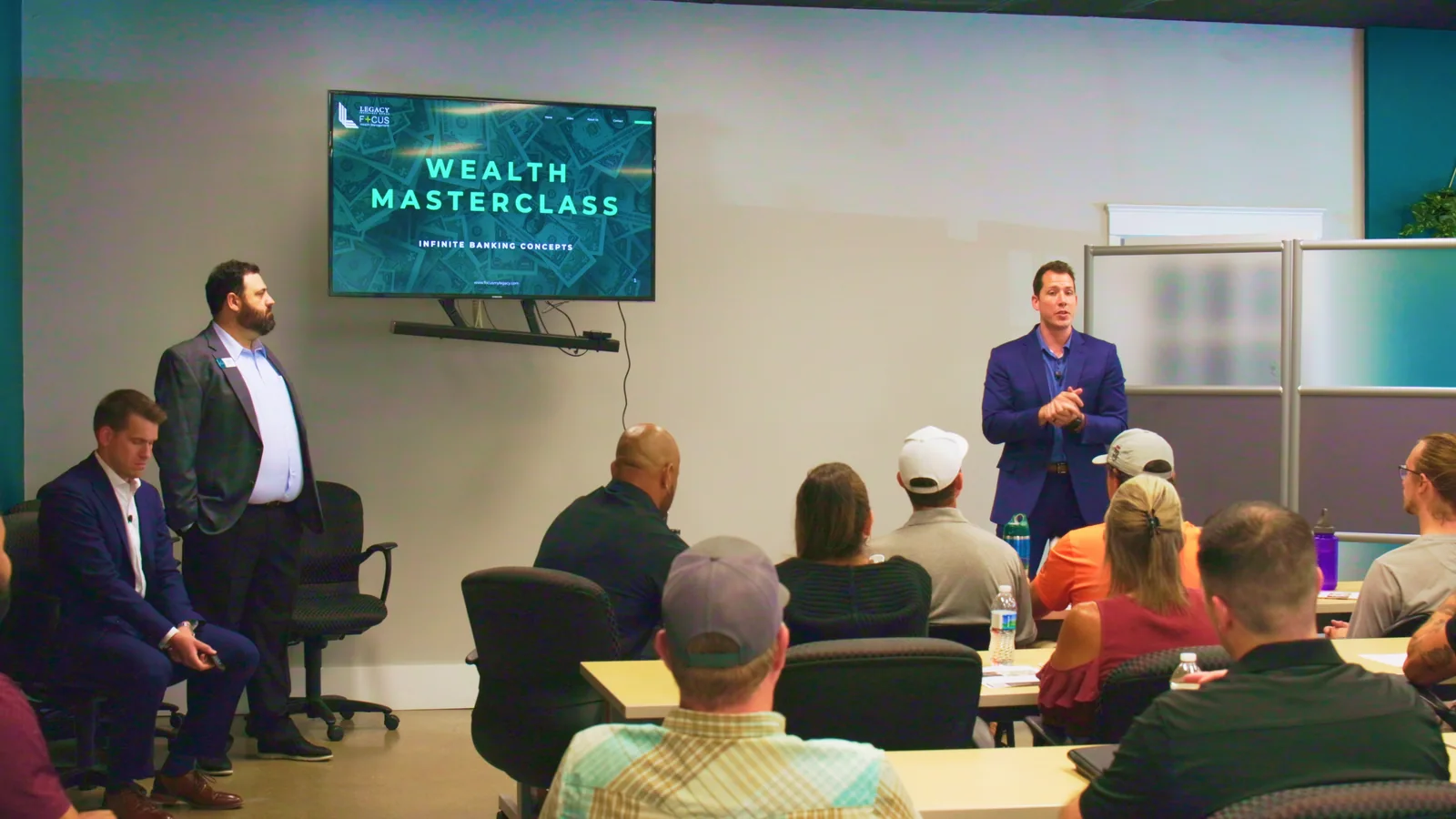 Two presenters speak to a seated audience at a Money 202 event.